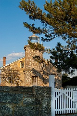 Stone Lighthouse Behind Stone Wall and Picket Fence